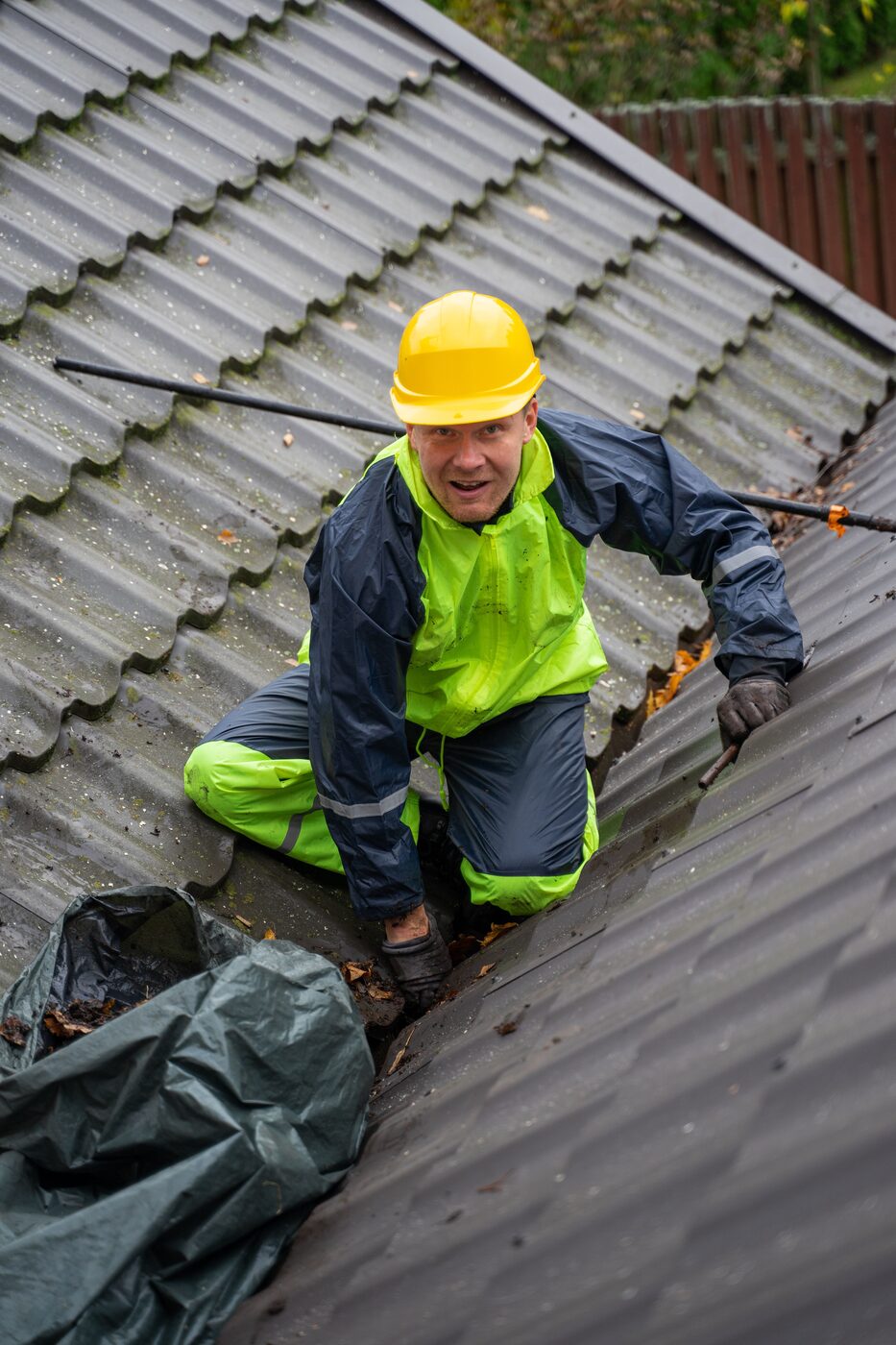 Gutter cleaning technician clearing leaves and debris from a Sydney roof gutter in full safety gear