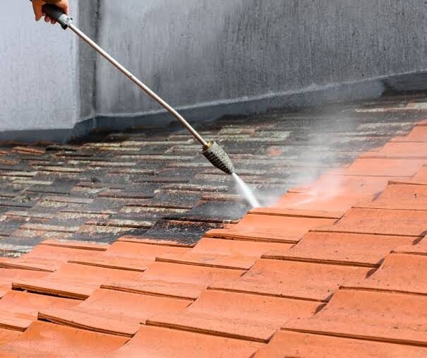 Pressure washing a terracotta tile roof to remove moss and grime